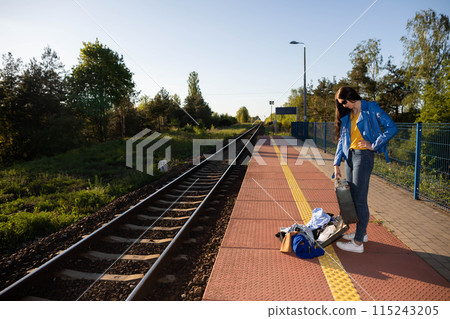 Teenagers spilled the contents of a travel suitcase on the train platform. An unfastened travel suitcase. Adventure on the platform. Teenagers spilled the contents of a travel suitcase on the train platform. An unfastened travel suitcase. Adventure on the platform. 115243205