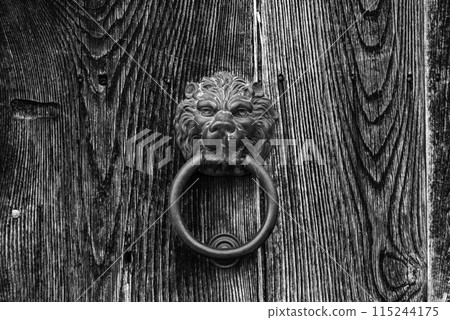Old-fashioned door knocker in shape of a lion head somewhere on a door in downtown Matera 115244175