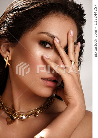 Beautiful tanned woman with smoky makeup, gold jewelry and ice. Beauty face. Beautiful tanned woman with smoky makeup, gold jewelry and ice. Beauty face. 115244257
