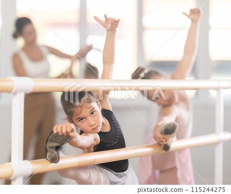 Girls dancers doing stretching at barre 115244275