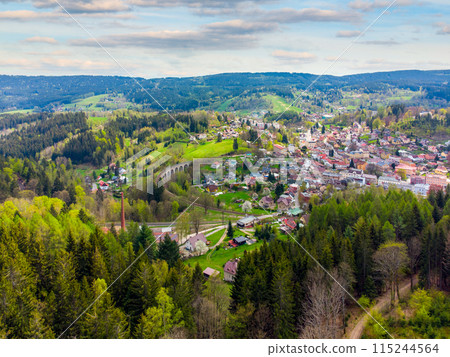 A vibrant springtime panorama over Smrzovka town, nestled amidst lush green hills and forests under a partly cloudy sky. Czechia A vibrant springtime panorama over Smrzovka town, nestled amidst lush green hills and forests under a partly cloudy sky. Czechia 115244564