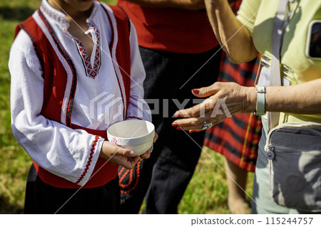 Unrecognizable boy in ethnic Bulgarian costume holding honey or salt. traditional welcome with bread, honey and salt Unrecognizable boy in ethnic Bulgarian costume holding honey or salt. traditional welcome with bread, honey and salt 115244757