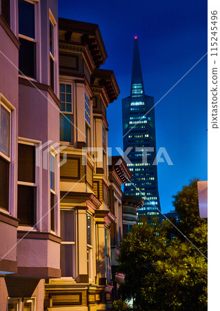 Eerily lit apartment buildings at night with Transamerica Pyramid looming out of fog 115245496