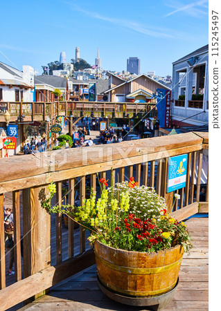 Deck with assorted colorful flowers in barrel on Pier 39 with distant Coit Tower 115245497