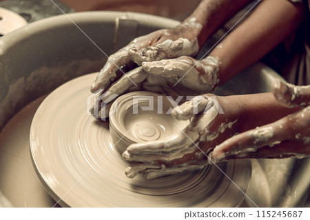 Close up picture of hands working with wet clay and molding its shape 115245687