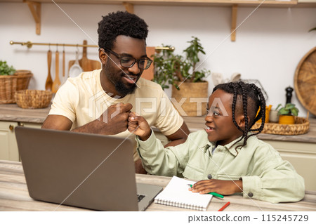 Father with schoolgirl daughter using laptop for doing homework during remote studying 115245729
