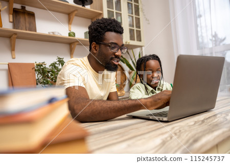 Black man with his daughter using laptop together while doing homework 115245737