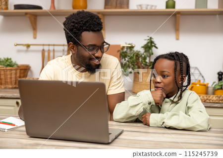 Black man with his daughter using laptop together while doing homework Black man with his daughter using laptop together while doing homework 115245739