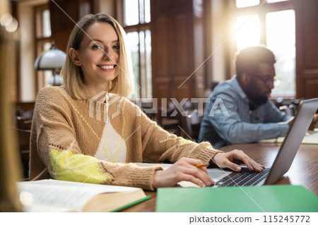 Blonde smiling woman at the laptop in the library 115245772
