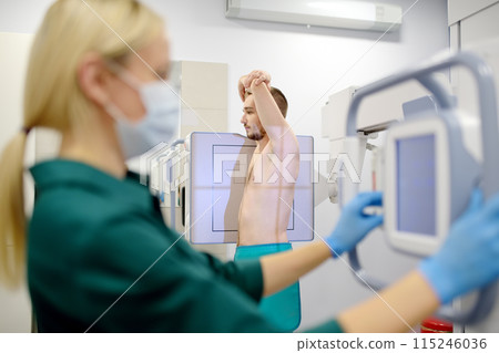 Female radiologist is making an Xray of lungs of patient in X-ray room of modern clinic. Doctor performs a fluorography. Medical examination of people is prevention of tuberculosis spread 115246036