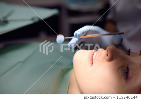 Dentist and patient at modern medical center. Doctor treats a young woman teeth in hospital. Practitioner examines the patient before orthodontists or prosthetics treatment. Dentist and patient at modern medical center. Doctor treats a young woman teeth in hospital. Practitioner examines the patient before orthodontists or prosthetics treatment. 115246144
