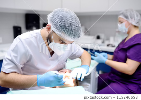Dentist and patient at modern medical center. Doctor treats a young woman teeth in hospital. Practitioner examines the patient before orthodontists or prosthetics treatment. Dentist and patient at modern medical center. Doctor treats a young woman teeth in hospital. Practitioner examines the patient before orthodontists or prosthetics treatment. 115246658