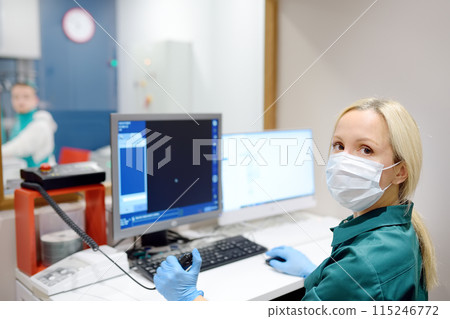 Female radiologist is going to take X ray of patient in X-ray room of modern clinic. Close up photo of doctor hand presses button for execute of medical examination 115246772