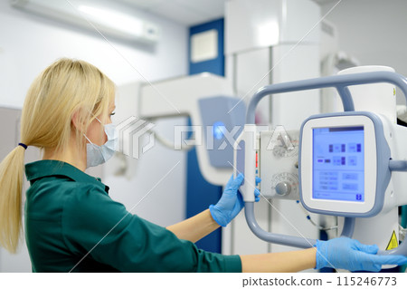 Female technician adjusts X-Ray machine. Female radiologist is going to take an Xray of patient in X-ray room of modern clinic. Female technician adjusts X-Ray machine. Female radiologist is going to take an Xray of patient in X-ray room of modern clinic. 115246773