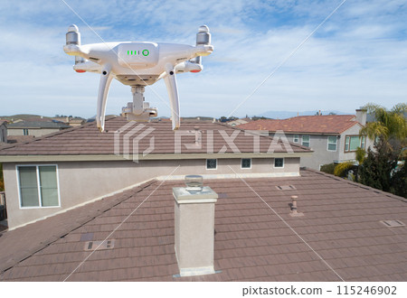 Quadcopter UAV Drone Flying A Residential Roof Inspection. Quadcopter UAV Drone Flying A Residential Roof Inspection. 115246902