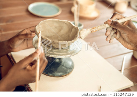 Close up of a human hand with a brush and a clay mug Close up of a human hand with a brush and a clay mug 115247129