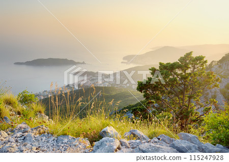 Aerial view of Budva Riviera from Fort Kosmach at sunset. Old fortress ruins is located in mountains near Budva in Montenegro. Amazing panoramic landscape of Adriatic coast with Saint Nikolay Island 115247928