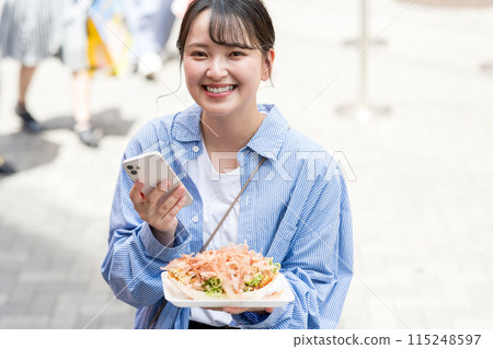 A young, cute, SNS-loving woman taking a photo of takoyaki with her smartphone outdoors in bright light | Dotonbori Shopping Street, Osaka City, Osaka Prefecture A young, cute, SNS-loving woman taking a photo of takoyaki with her smartphone outdoors in bright light | Dotonbori Shopping Street, Osaka City, Osaka Prefecture 115248597