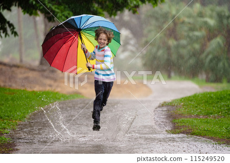Child playing in rain. Kid jumping in puddle. Child playing in rain. Kid jumping in puddle. 115249520