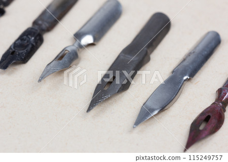 Metal nibs on an antique textured paper. 115249757