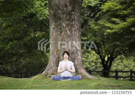 A woman meditating in front of a large tree - Outdoor yoga image A woman meditating in front of a large tree - Outdoor yoga image 115250755