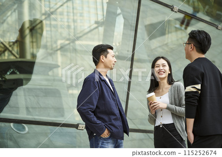three young asian adults standing talking on street three young asian adults standing talking on street 115252674