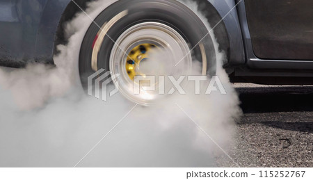 Drag racing car burning tire at starting line in race track 115252767