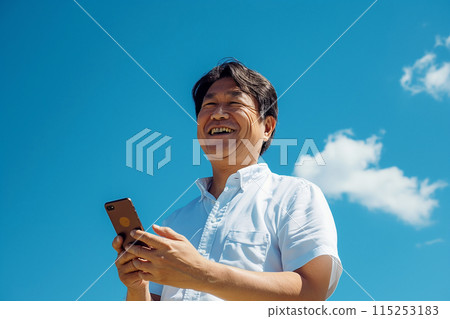 A businessman operating a smartphone under the blue sky A businessman operating a smartphone under the blue sky 115253183