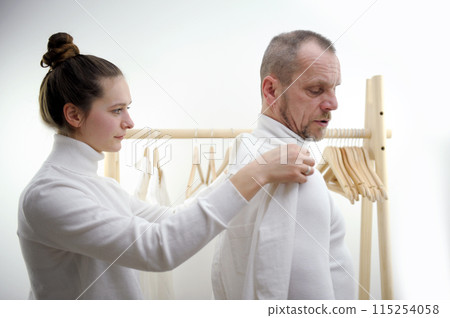 Tailor standing near male client measuring back. Tailor woman taking measures for new business shirt using tape meter. Young fashion designer taking measurement of man wearing shirt in store. Tailor standing near male client measuring back. Tailor woman taking measures for new business shirt using tape meter. Young fashion designer taking measurement of man wearing shirt in store. 115254058