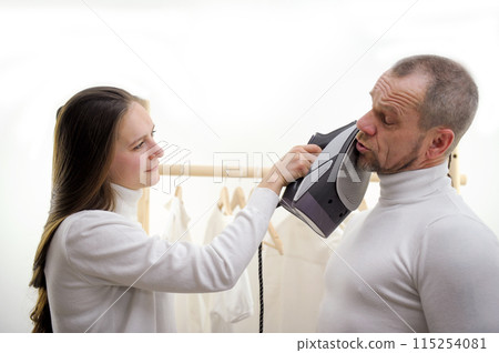 Closeup portrait of angry young woman hitting surprised shocked funny man on face with iron, isolated on white background. Negative emotion facial expression feelings, reaction, situation. Closeup portrait of angry young woman hitting surprised shocked funny man on face with iron, isolated on white background. Negative emotion facial expression feelings, reaction, situation. 115254081
