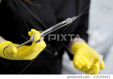 Black clothes long flowing hair white cabinet office dentistry Young girl woman with syringe in hand anaesthesia yellow gloves doctor nurse Doctor, girl, syringe injection 115254451