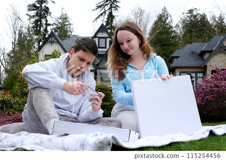 boys girl with pizza boxes of sweets empty boxes with white background for advertising inscriptions space For text on picnic in hands with phone schoolchildren friends teenagers First love date boys girl with pizza boxes of sweets empty boxes with white background for advertising inscriptions space For text on picnic in hands with phone schoolchildren friends teenagers First love date 115254456