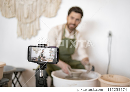 Potter making clay vase while recording video blog Potter making clay vase while recording video blog 115255574