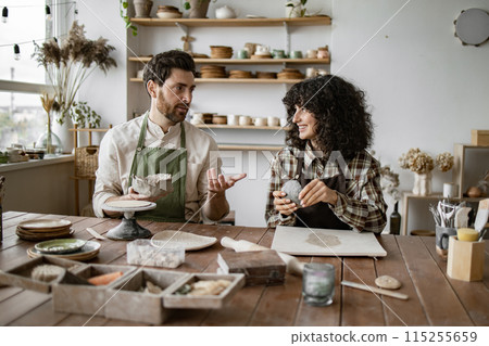 Mature man and woman sculpting clay pottery in studio Mature man and woman sculpting clay pottery in studio 115255659