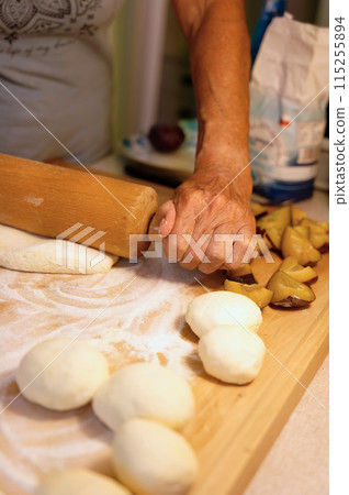 Preparation of homemade fruit dumplings with plums. Czech specialty of sweet good food. Dough on kitchen wooden table with hands. 115255894