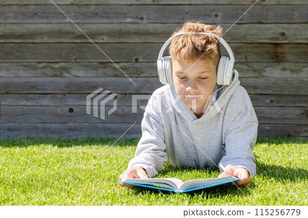 A boy relaxing on grass, listening to music A boy relaxing on grass, listening to music 115256779