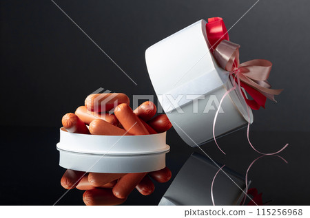 Opened gift box with sausages on a black background. Opened gift box with sausages on a black background. 115256968