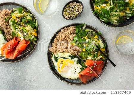 Buckwheat with fried egg and salmon fish, mix salad with fresh herbs and peppers 115257469