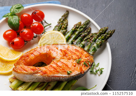 Grilled salmon steak over grilled asparagus, a delicious meal 115257510