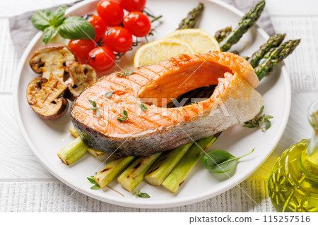 Grilled salmon steak over grilled asparagus, a delicious meal 115257516