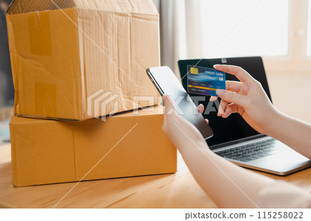 close up phone and credit card in online seller woman's hand with box background close up phone and credit card in online seller woman's hand with box background 115258022