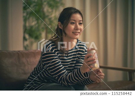 一個女人在房間裡喝啤酒 一個女人在房間裡喝啤酒 115258442
