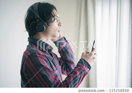 A young man listening to music on a smartphone A young man listening to music on a smartphone 115258830
