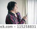 A young man listening to music on a smartphone 115258831