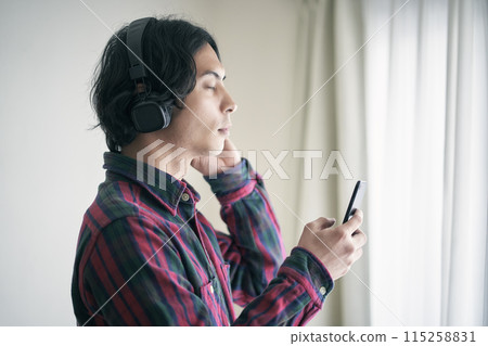 A young man listening to music on a smartphone A young man listening to music on a smartphone 115258831