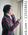 A young man listening to music on a smartphone 115258832