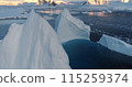 Huge towering icebergs melt in blue ocean bay. Arctic landscape. Ice glacier polar nature environment. Arctic winter landscape, global warming. Climate change in sunset landscape. Close up aerial shot 115259374