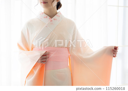 A woman getting dressed in a kimono A woman getting dressed in a kimono 115260018