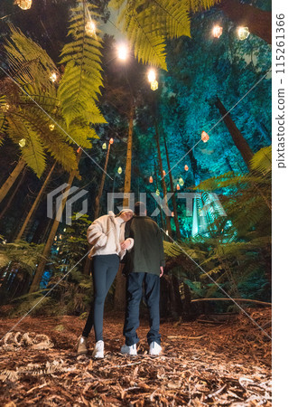 Asian couple tourist enjoying in Redwood or Whakarewarewa forest with illuminated lighting and lamp at New Zealand 115261366