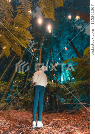 Female tourist enjoying in Redwood or Whakarewarewa forest with illuminated lighting in the night at New Zealand 115261367